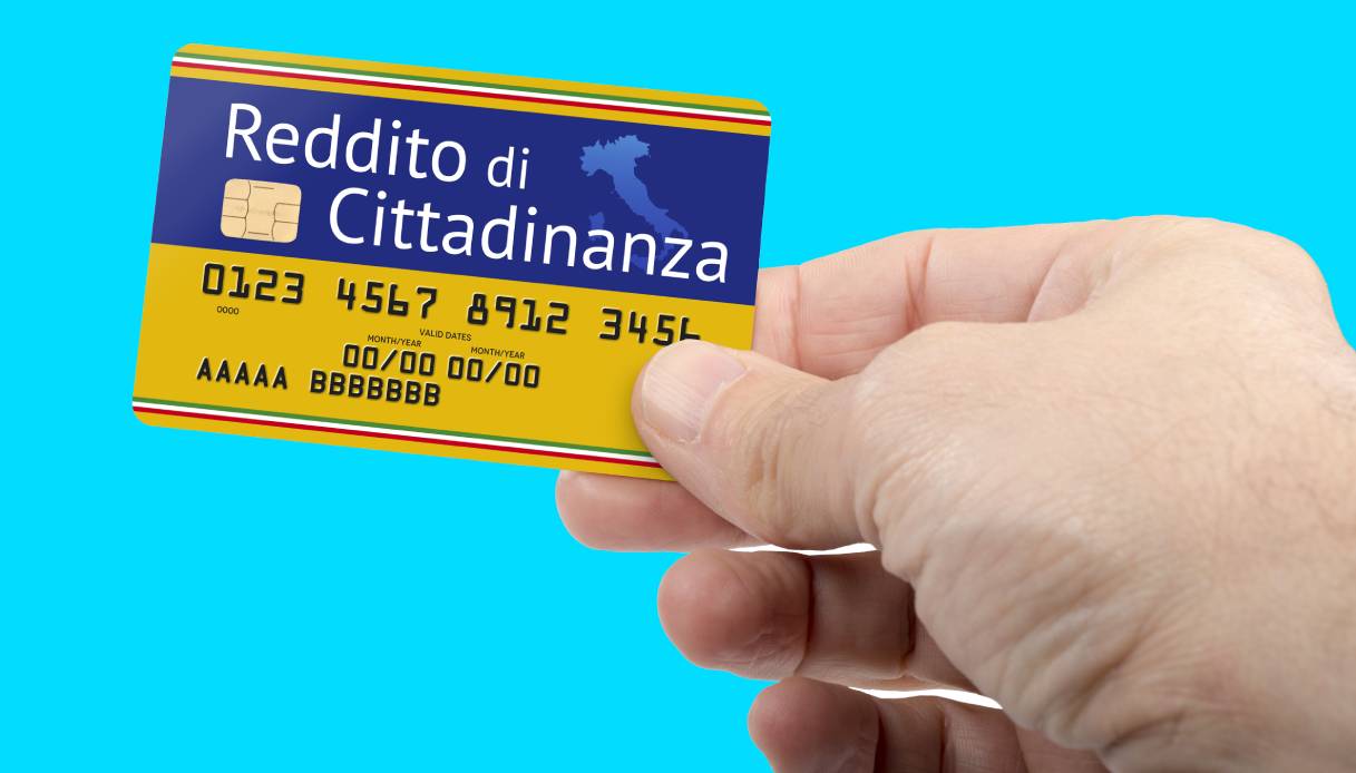 Mano che tiene una carta del Reddito di Cittadinanza su sfondo azzurro