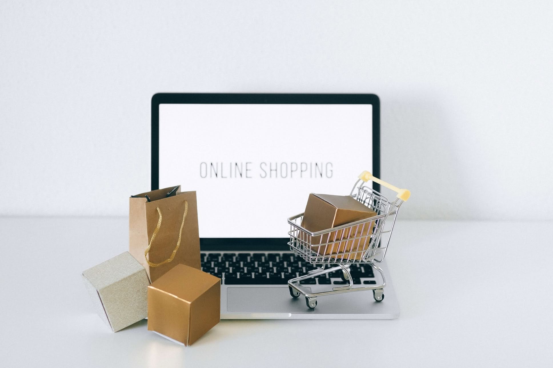 Carrello, pacchi e scritta "online shopping" su schermo: simbolo di e-commerce e tutela dei dati